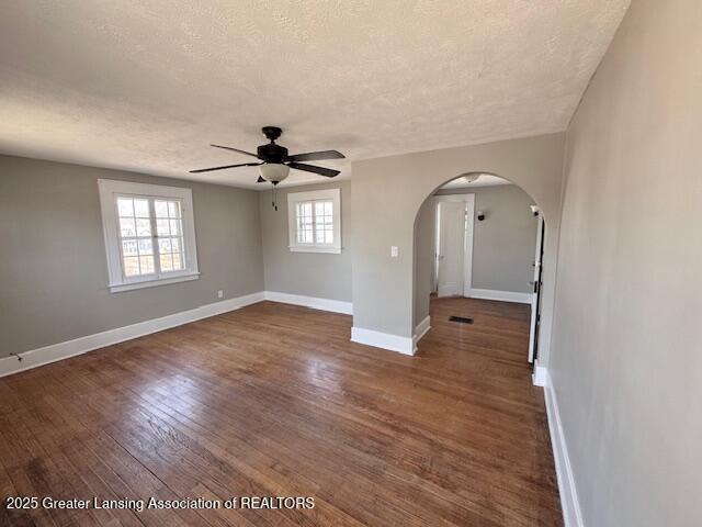 1305 W Hillsdale St, Lansing, MI 48915 - unfurnished room with a textured ceiling, arched walkways, ceiling fan, baseboards, and wood finished floors