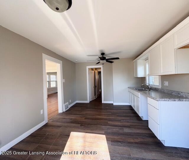1305 W Hillsdale St, Lansing, MI 48915 - kitchen with a sink, white cabinets, baseboards, and a ceiling fan