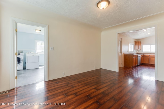309 W Plain St, Eaton Rapids, MI 48827 - unfurnished living room with a textured ceiling, dark wood-type flooring, and washer and dryer