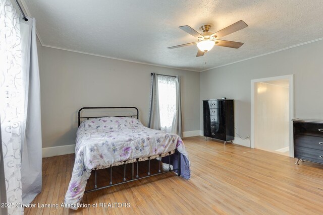309 W Plain St, Eaton Rapids, MI 48827 - bedroom with wood finished floors, ornamental molding, a textured ceiling, baseboards, and a ceiling fan