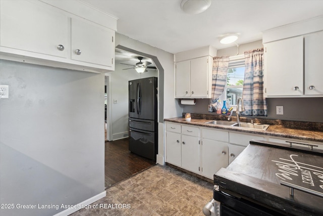 3804 Glenwood Ave, Lansing, MI 48910 - kitchen with black fridge, a sink, ceiling fan, and white cabinetry