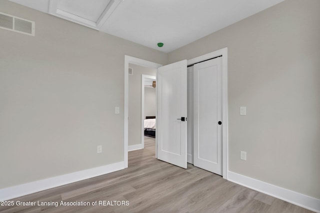 3115 Dietz Rd, Williamston, MI 48895 - unfurnished bedroom featuring light wood-style floors, attic access, baseboards, and a closet