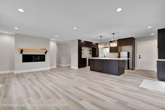 3115 Dietz Rd, Williamston, MI 48895 - kitchen with open floor plan, refrigerator, dark brown cabinetry, light countertops, and light wood-style floors