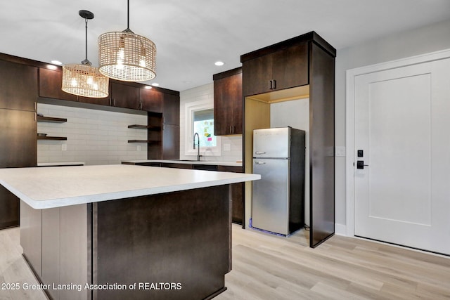 3115 Dietz Rd, Williamston, MI 48895 - kitchen featuring freestanding refrigerator, open shelves, dark brown cabinets, light countertops, and tasteful backsplash