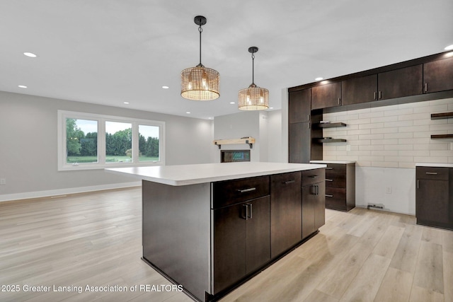 3115 Dietz Rd, Williamston, MI 48895 - kitchen featuring open shelves, light wood finished floors, light countertops, dark brown cabinets, and a kitchen island