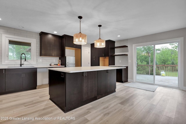 3115 Dietz Rd, Williamston, MI 48895 - kitchen featuring a sink, a kitchen island, open shelves, tasteful backsplash, and light countertops