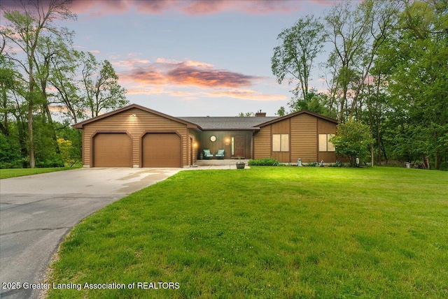 4582 N Watson Rd, Elsie, MI 48831 - view of front facade with an attached garage, concrete driveway, a yard, and a chimney