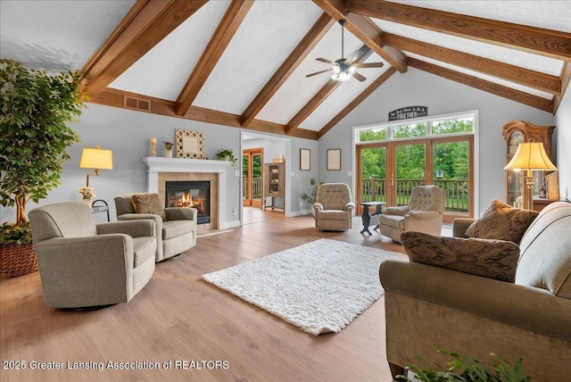 4582 N Watson Rd, Elsie, MI 48831 - living room with beam ceiling, high vaulted ceiling, ceiling fan, a glass covered fireplace, and wood finished floors