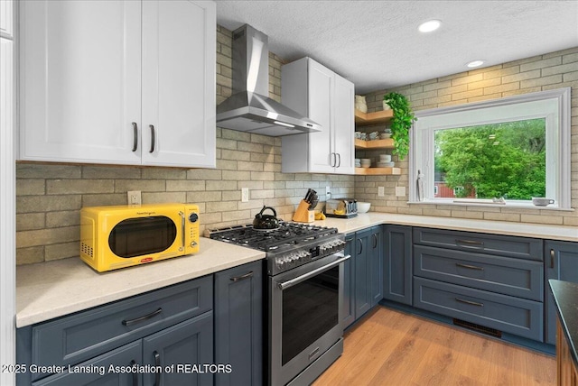 4582 N Watson Rd, Elsie, MI 48831 - kitchen featuring gas stove, wall chimney exhaust hood, white cabinetry, a textured ceiling, and light wood finished floors