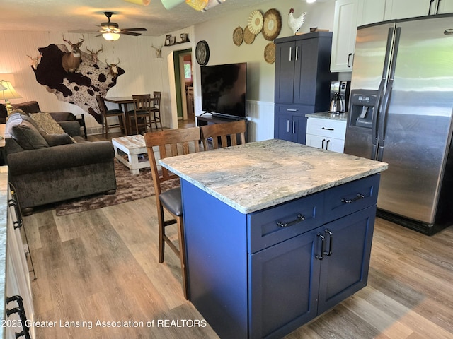 3066 S Canfield Rd, Eaton Rapids, MI 48827 - kitchen featuring stainless steel fridge with ice dispenser, blue cabinetry, a ceiling fan, and light wood finished floors