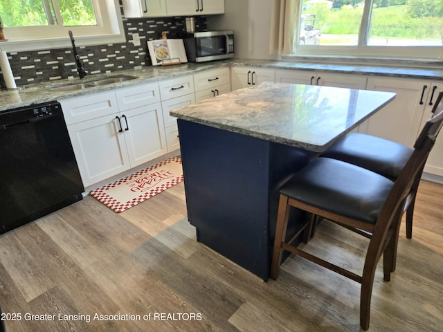 3066 S Canfield Rd, Eaton Rapids, MI 48827 - kitchen with black dishwasher, a sink, light wood-style floors, stainless steel microwave, and white cabinetry