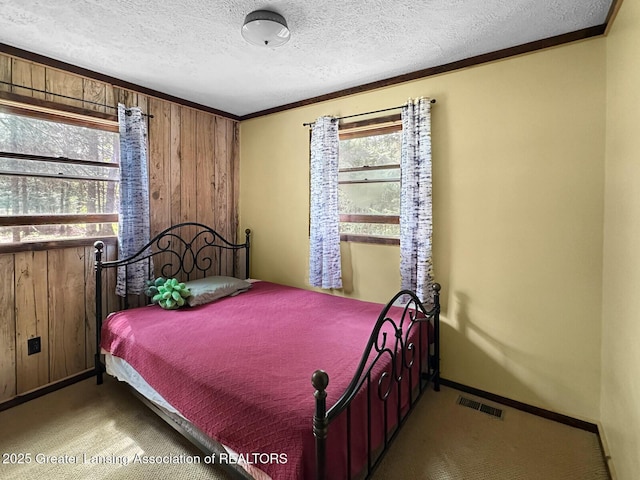 2623 Timberlane Trl, Grayling, MI 49738 - carpeted bedroom with wood walls, a textured ceiling, ornamental molding, and baseboards