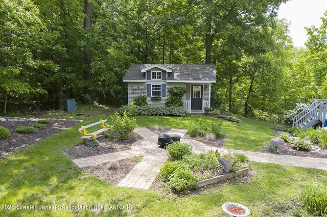 11781 W Herbison Rd, Eagle, MI 48822 - view of green lawn featuring an outbuilding, a fire pit, and a vegetable garden