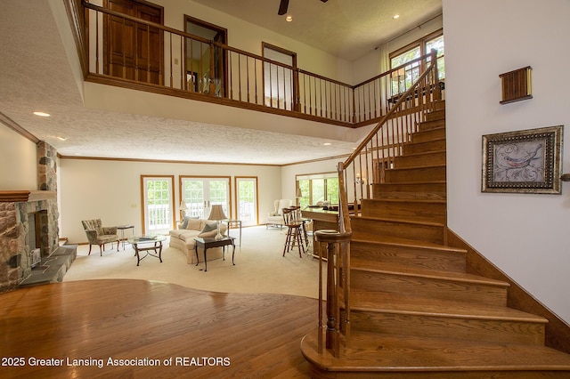 11781 W Herbison Rd, Eagle, MI 48822 - staircase with a stone fireplace, recessed lighting, carpet, ornamental molding, and a towering ceiling