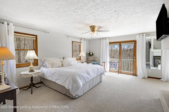 11781 W Herbison Rd, Eagle, MI 48822 - carpeted bedroom featuring access to exterior, a glass covered fireplace, a textured ceiling, a ceiling fan, and baseboards