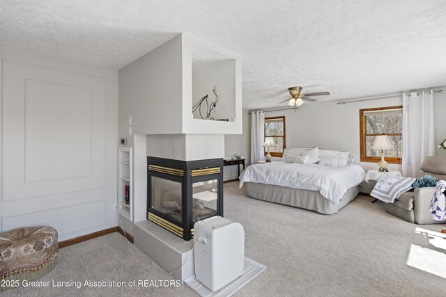 11781 W Herbison Rd, Eagle, MI 48822 - bedroom featuring a textured ceiling, a tile fireplace, carpet flooring, and a ceiling fan