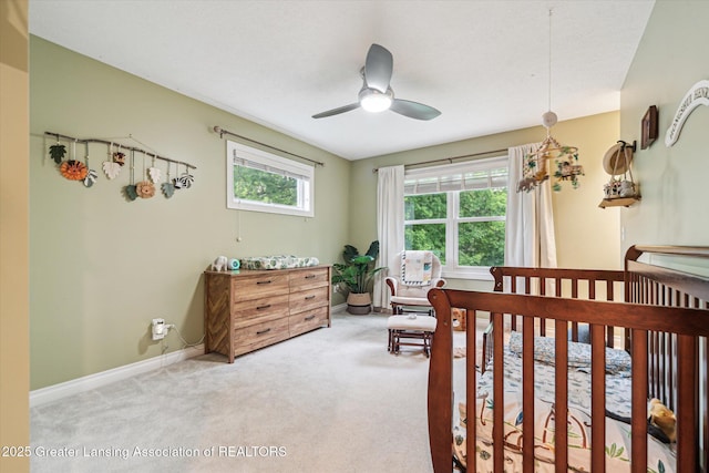 1058 Buckingham Rd, Haslett, MI 48840 - carpeted bedroom with a crib, baseboards, and ceiling fan