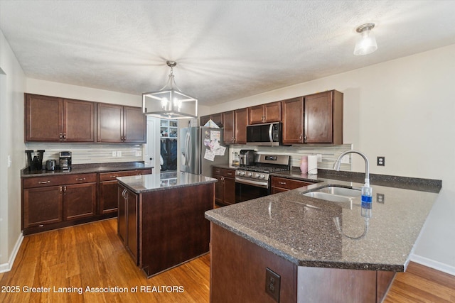 2705 Tapestry Dr Unit 53, Okemos, MI 48864 - kitchen with appliances with stainless steel finishes, a sink, a peninsula, wood finished floors, and tasteful backsplash