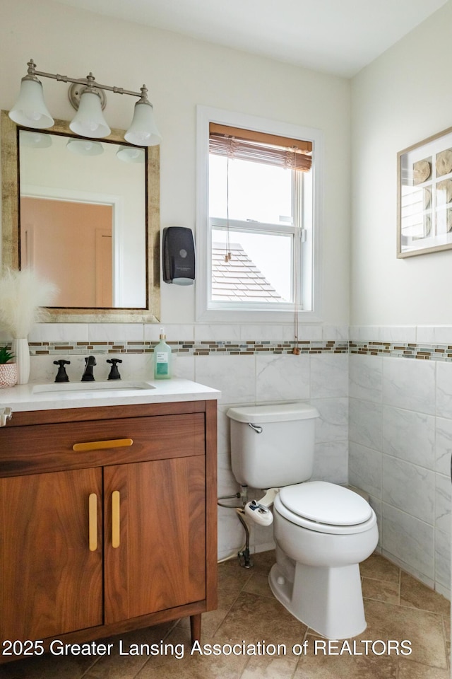 1100 Cranbrook Ln, Mason, MI 48854 - bathroom with vanity, toilet, tile patterned floors, a wainscoted wall, and tile walls