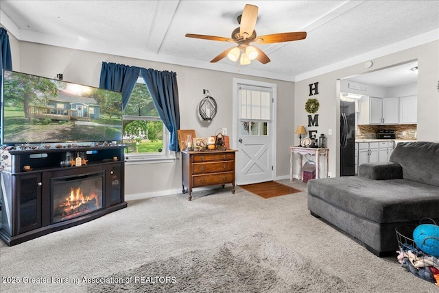 424 N Morrice Rd, Morrice, MI 48857 - carpeted living area featuring a ceiling fan, baseboards, and a glass covered fireplace