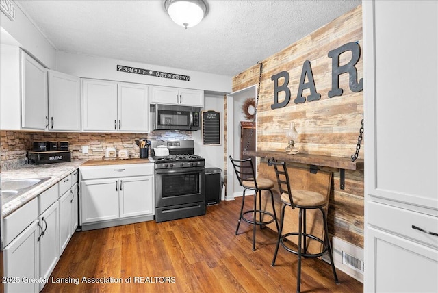 424 N Morrice Rd, Morrice, MI 48857 - kitchen with appliances with stainless steel finishes, white cabinetry, light countertops, a textured ceiling, and wood finished floors