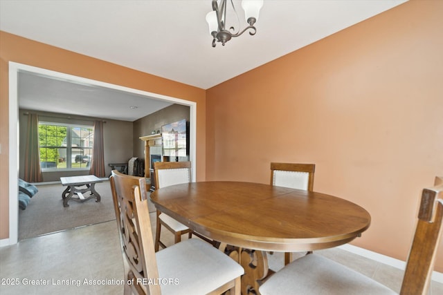 5619 Bittern Dr, Holt, MI 48842 - dining area with a fireplace, baseboards, carpet floors, and a chandelier