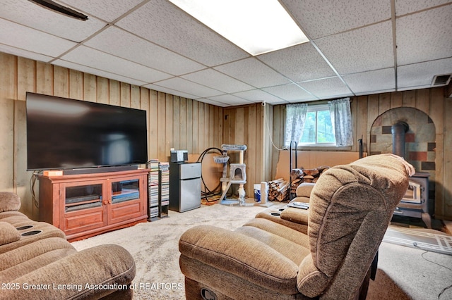 14311 Chandler Rd, Bath, MI 48808 - living room featuring a wood stove, carpet floors, wood walls, and a drop ceiling
