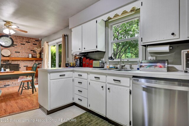 14311 Chandler Rd, Bath, MI 48808 - kitchen featuring stainless steel dishwasher, brick wall, light countertops, ceiling fan, and white cabinets
