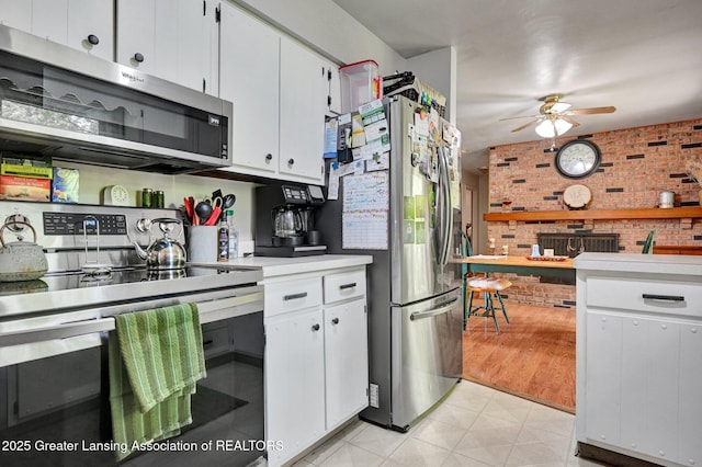 14311 Chandler Rd, Bath, MI 48808 - kitchen with appliances with stainless steel finishes, ceiling fan, brick wall, light countertops, and white cabinets