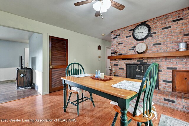 14311 Chandler Rd, Bath, MI 48808 - dining area with a brick fireplace, wood finished floors, and a ceiling fan