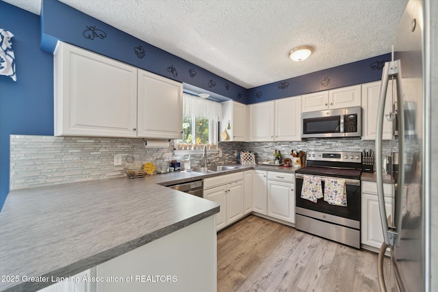 2500 Champion Way, Lansing, MI 48910 - kitchen featuring appliances with stainless steel finishes, a sink, a textured ceiling, light wood finished floors, and white cabinets