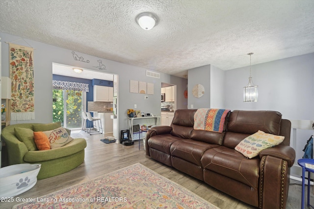 2500 Champion Way, Lansing, MI 48910 - living area featuring light wood finished floors, a textured ceiling, and a chandelier
