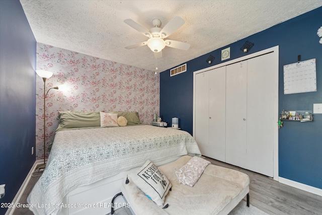 2500 Champion Way, Lansing, MI 48910 - bedroom with baseboards, wood finished floors, a closet, a textured ceiling, and a ceiling fan