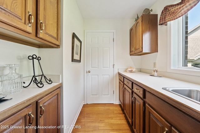 1209 Windale Pl, East Lansing, MI 48823 - kitchen featuring light countertops, light wood finished floors, brown cabinets, and baseboards