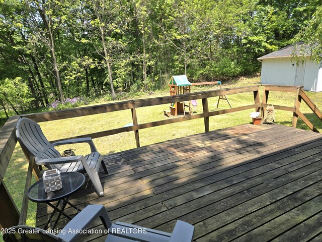 4423 Hyatt St, Eaton Rapids, MI 48827 - wooden terrace featuring a playground, a lawn, and a view of trees
