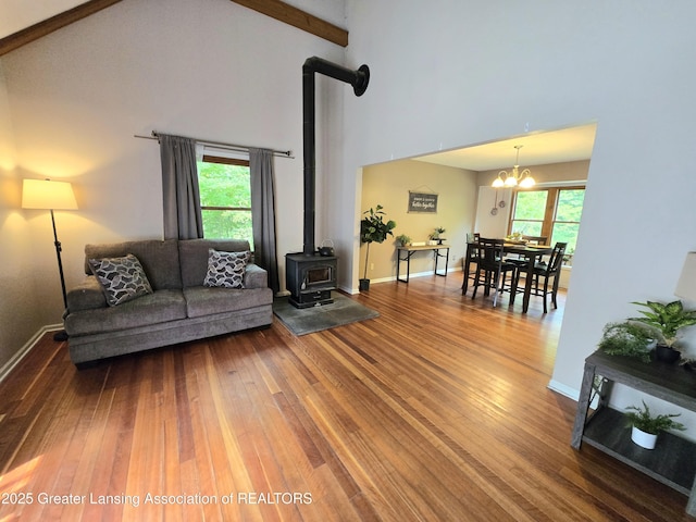 4423 Hyatt St, Eaton Rapids, MI 48827 - living area with a wood stove, wood finished floors, high vaulted ceiling, a chandelier, and healthy amount of natural light