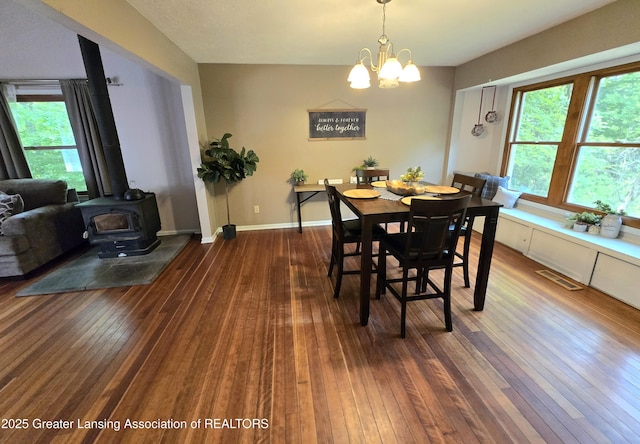 4423 Hyatt St, Eaton Rapids, MI 48827 - dining room with hardwood / wood-style floors, a wood stove, a chandelier, and baseboards