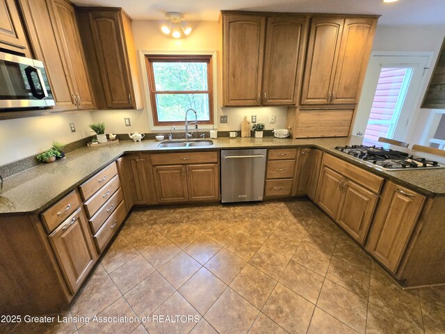 4423 Hyatt St, Eaton Rapids, MI 48827 - kitchen featuring a sink, stainless steel appliances, a peninsula, brown cabinets, and tile patterned flooring