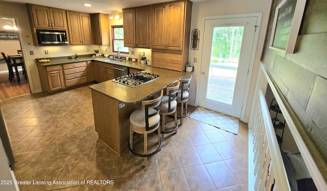4423 Hyatt St, Eaton Rapids, MI 48827 - kitchen with appliances with stainless steel finishes, brown cabinets, a kitchen bar, a sink, and recessed lighting