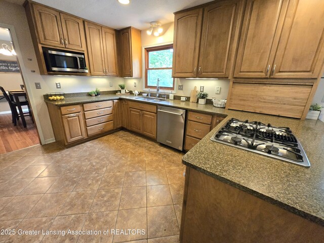 4423 Hyatt St, Eaton Rapids, MI 48827 - kitchen featuring appliances with stainless steel finishes, a sink, dark countertops, brown cabinetry, and light tile patterned flooring