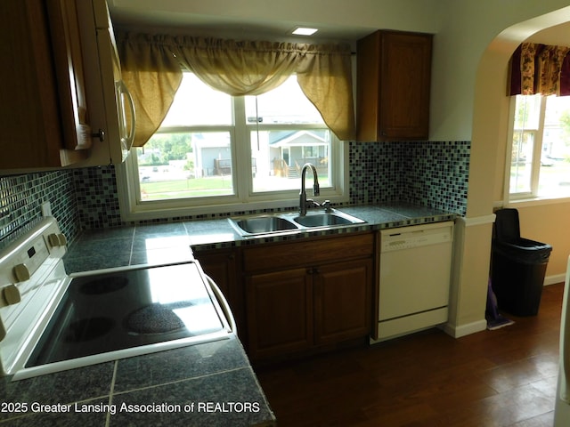 1305 May St, Lansing, MI 48906 - kitchen featuring white appliances, a sink, arched walkways, and backsplash