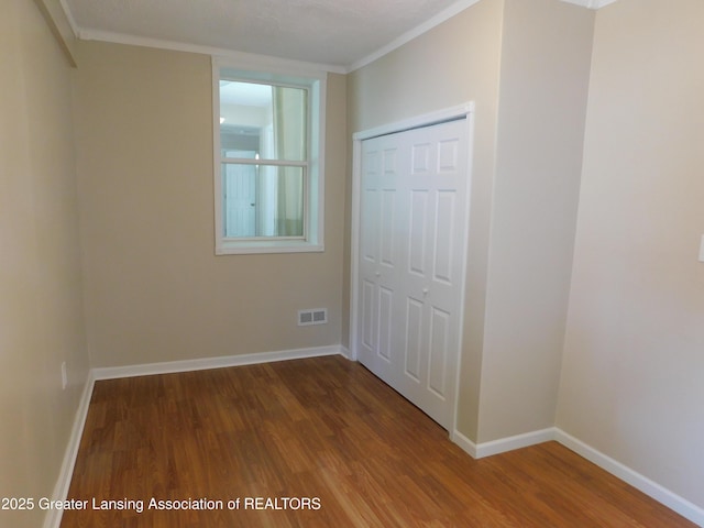 1305 May St, Lansing, MI 48906 - unfurnished bedroom featuring wood finished floors, baseboards, a closet, and ornamental molding
