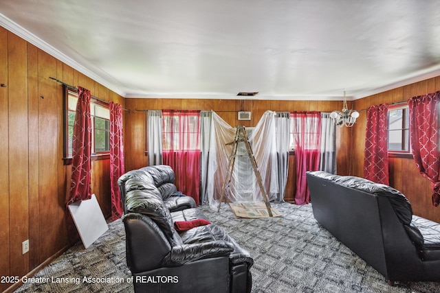 1615 Inverness Ave, Lansing, MI 48915 - living room featuring wood walls, carpet, ornamental molding, and a chandelier