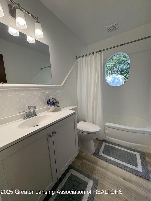 1524 Roseneath Ave, Lansing, MI 48915 - full bath featuring wood finished floors, vanity, toilet, shower / bath combo, and tasteful backsplash