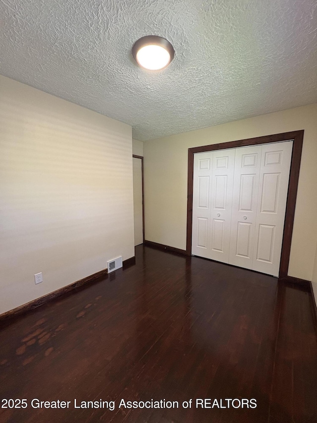 1524 Roseneath Ave, Lansing, MI 48915 - unfurnished bedroom with dark wood-type flooring, a closet, baseboards, and a textured ceiling