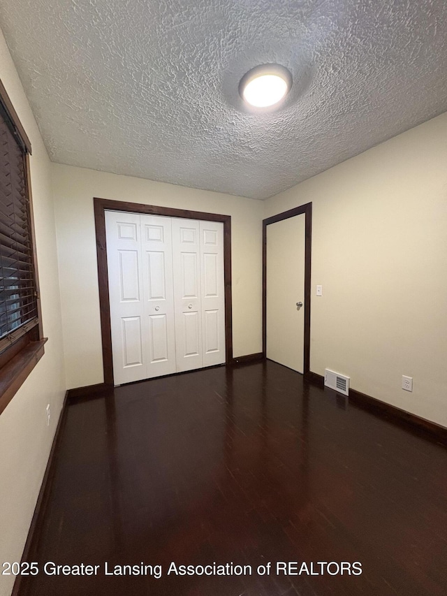 1524 Roseneath Ave, Lansing, MI 48915 - unfurnished bedroom with wood finished floors, baseboards, a closet, and a textured ceiling
