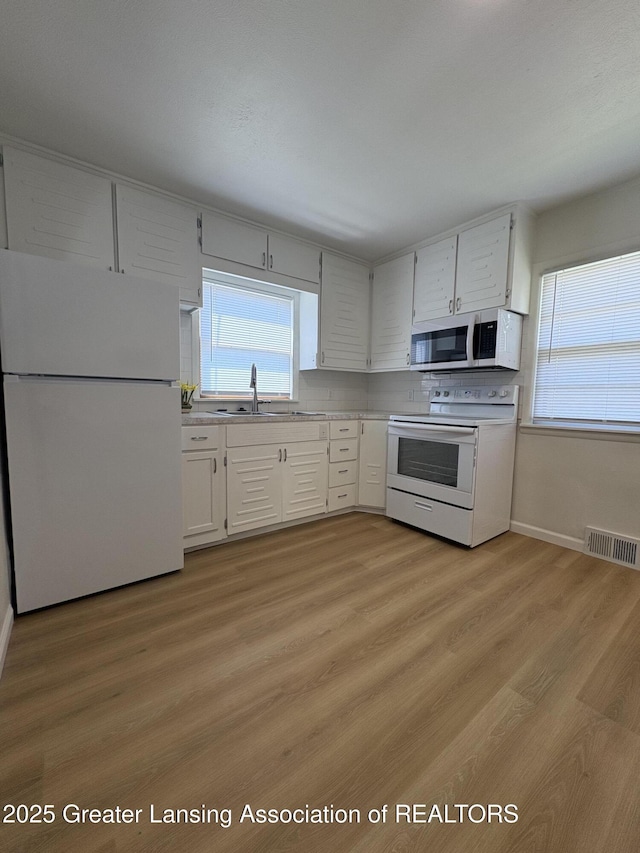 1524 Roseneath Ave, Lansing, MI 48915 - kitchen featuring white appliances, a sink, light countertops, light wood-style floors, and baseboards
