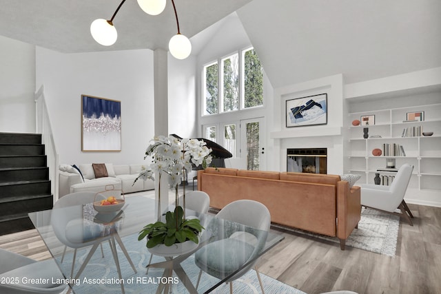 4003 Norfolk Ct, Lansing, MI 48910 - living area with light wood-style floors, high vaulted ceiling, stairs, a glass covered fireplace, and built in features