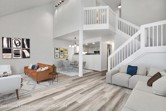 4003 Norfolk Ct, Lansing, MI 48910 - living room featuring wood finished floors, stairs, a towering ceiling, a chandelier, and baseboards
