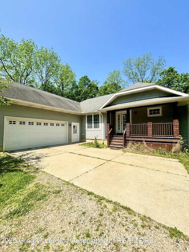 1826 Battle Creek Rd, Charlotte, MI 48813 - view of front of home featuring french doors, concrete driveway, a garage, and covered porch